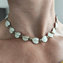 Load image into Gallery viewer, A white enamel leaf necklace in silver gilt, modelled by a woman
