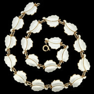 A white enamel leaf necklace in silver gilt, on a black background