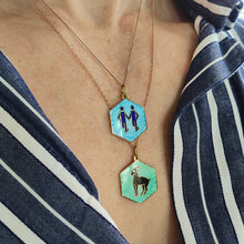 Load image into Gallery viewer, Two enamelled hexagonal zodiac pendants with chains, modelled by a woman wearing a stripey shirt
