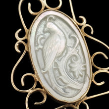 Load image into Gallery viewer, A close-up of an oval yellow gold and mother of pearl pendant carved with a bird, on a black background
