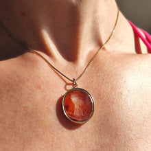 Load image into Gallery viewer, An oval carnelian intaglio pendant displaying a wheatsheaf, with a chain, modelled by a woman
