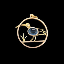 Load image into Gallery viewer, A circular cutout pendant featuring a wading bird with a blue paste stone body, in yellow gold, on a black background
