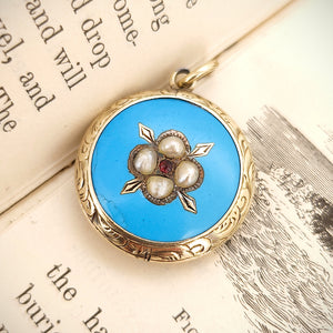Victorian 9ct Gold Enamel, Pearl and Garnet Glazed Back Pendant sat on the open pages of a book