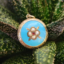 Load image into Gallery viewer, Victorian 9ct Gold Enamel, Pearl and Garnet Glazed Back Pendant sat amongst leaves
