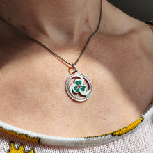 Load image into Gallery viewer, A silver enamel clover triskelion pendant, on a chain, modelled by a woman
