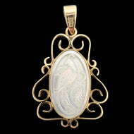 An oval yellow gold and mother of pearl pendant carved with a bird, on a black background