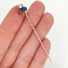 Load image into Gallery viewer, A ruby, sapphire and diamond clover shaped stick tie pin in gold, held in a hand
