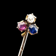 Load image into Gallery viewer, A ruby, sapphire and diamond clover shaped stick tie pin in gold, on a black background
