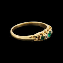 Load image into Gallery viewer, An emerald and diamond graduated five stone ring in yellow gold, on a black background
