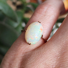 Load image into Gallery viewer, A single stone oval shaped, cabochon cut opal ring in rose gold, modelled on a hand
