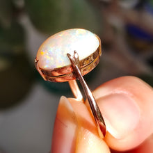 Load image into Gallery viewer, A single stone oval shaped, cabochon cut opal ring in rose gold, held in a hand
