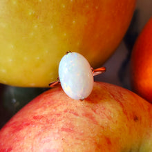 Load image into Gallery viewer, A single stone oval shaped, cabochon cut opal ring in rose gold, in between two apples
