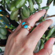 Load image into Gallery viewer, A rose gold double snake band ring with turquoise heads, modelled on a hand
