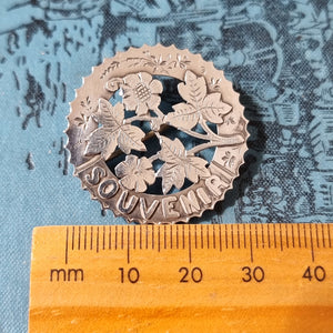 Antique Silver Souvenir Flower Brooch next to ruler
